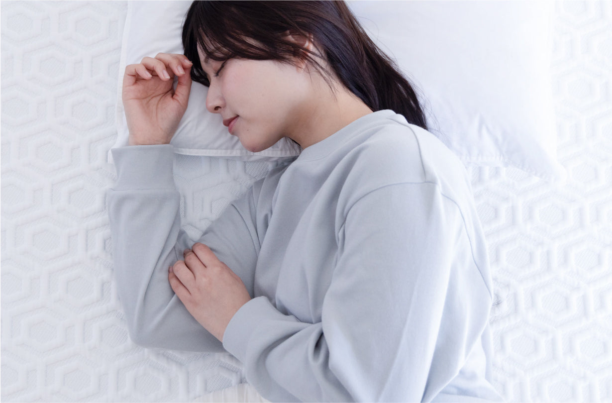 リカバリーウェアを着て気持ちよさそうに寝る女性